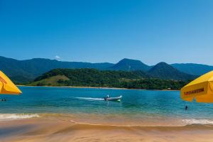 a man in a boat in the water on a beach at Loft central perto da praia in Caraguatatuba