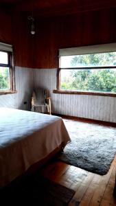 une chambre avec un lit et une grande fenêtre dans l'établissement Refugio Kallfuko, a great space with nature, à Valdivia