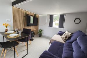 a living room with a blue couch and a table at Loft central perto da praia in Caraguatatuba