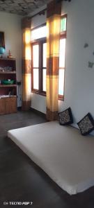 a room with a large white bed with two windows at Villa Tharu in Hikkaduwa