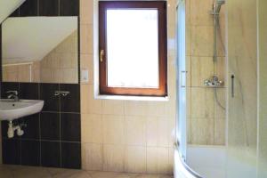 een badkamer met een wastafel en een douche met een raam bij Holiday apartment with fireplace, lake view in Kiedrowice +28 foto's
