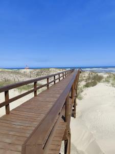 una passerella di legno che si estende sulla sabbia della spiaggia di Village Hakuna a Balneário Gaivotas Altre 12 foto