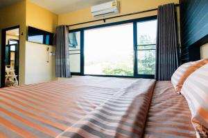 a large bed in a room with a large window at Sethachan Poolvilla Khaoyai in Ban Rai Khlong Sai