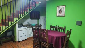 een keuken met groene muren, een tafel en een trap bij Posada del Sol in Ituzaingó