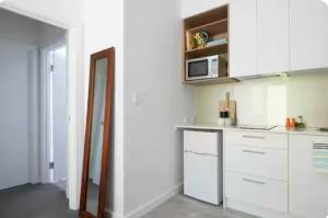 une cuisine avec des armoires blanches et un micro-ondes dans l'établissement Fremantle Harbour Studio, à Fremantle