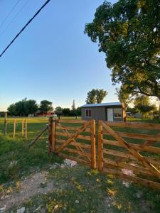 una recinzione di legno in un campo con una casa sullo sfondo di Quintas Baradero a Baradero