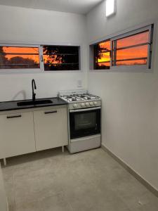 una cucina con piano cottura e lavandino e 2 finestre di Quintas Baradero a Baradero