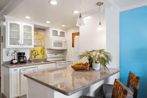 a kitchen with white cabinets and a bowl of fruit on a counter at Lahaina Shores 212 in Lahaina