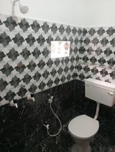 een badkamer met een toilet en zwarte en witte tegels bij Surya Vinayak Homestay in Ghātsīla
