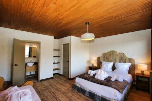 una camera da letto con letto, cuscini bianchi e soffitto in legno di Chalet Arpian Valmorel a Les Avanchers
