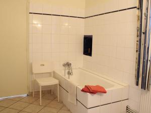 een witte badkamer met een bad en een kruk bij Gîte lumineux dans ancienne orangerie avec jardin et barbecue - FR-1-489-281 in Trézelles