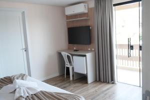 a bedroom with a desk with a tv and a bed at Hotel La Roza e Restaurante Grill in Penha