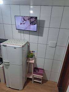 a white refrigerator in a room with a small table at Sobradinho Morro dos Ventos in Palhoça