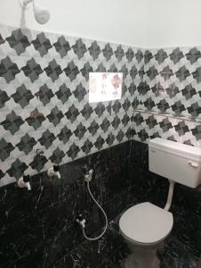 a bathroom with a toilet and black and white tiles at SuryaVinayak Home Stay - 10min walk from Railway station in Ghātsīla