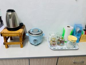 a kitchen counter with a coffee maker and jars on a table at Homestay Hayyan in Kampong Terbak