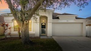 una casa bianca con un albero di fronte di NEW - Poolside Oasis Heated POOL Home - 2000 SF a Zephyrhills