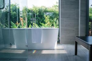 a bath tub in a bathroom with a large window at Lamori Resort & Spa, Thanh Hoá in Thanh Hóa