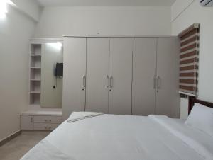een slaapkamer met witte kasten en een wit bed bij Amaira Studio living - Coimbatore in Coimbatore