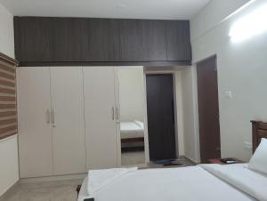 een slaapkamer met een bed met witte kasten en een spiegel bij Amaira Studio living - Coimbatore in Coimbatore +1 foto