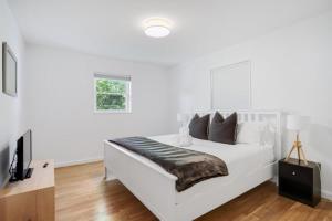 een witte slaapkamer met een bed en een televisie bij Forest Glen Silver Spring Gem - Parking in Silver Spring