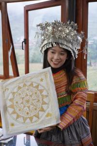 a young girl wearing a hat and holding a shield at PaoDzung Homestay Sapa in Sapa
