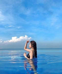 头顿Center Point The Sóng Vung Tau - Infinity Pool的坐在海洋水中的女人