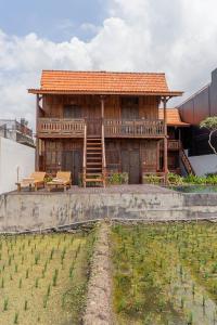 ein Holzhaus mit Bänken auf einem Feld in der Unterkunft Kalyana Gangga in Krambitan
