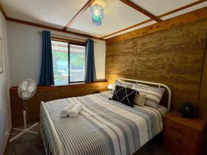 ein Schlafzimmer mit einem Bett mit einer Holzwand in der Unterkunft Macbeth Family Stay in Busselton