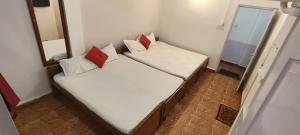 two beds in a small room with red and white pillows at Marlin Beachway Rooms- Baga Beach in Baga