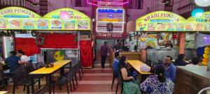 a group of people sitting at tables in a restaurant at Marlin Beachway Rooms- Baga Beach in Baga