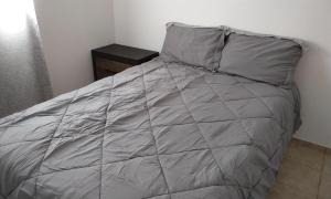 a bed with gray sheets and pillows in a bedroom at Claudette Guest House in Michelson