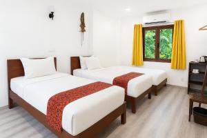 twee bedden in een kamer met gele gordijnen bij Paradise K Forest Hotel in Siem Reap