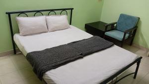 a bedroom with a bed and a blue chair at Cherry Blossom in Puducherry