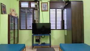a living room with a tv and some windows at Cherry Blossom in Puducherry