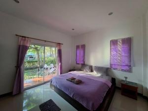 a bedroom with a bed with purple sheets and a window at Little Purple House- AoNang in Ao Nang 