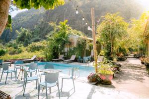 Un patio con mesas y sillas junto a una piscina. en Cat Ba Countryside Homestay, en Cat Ba