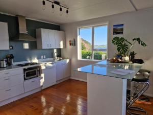 een keuken met witte kasten en een groot raam bij Country Harbourside Escape in Whakapirau