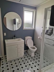 een badkamer met een toilet, een wastafel en een spiegel bij Country Harbourside Escape in Whakapirau
