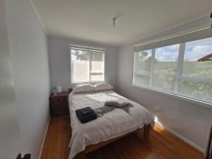 een slaapkamer met een bed en een groot raam bij Country Harbourside Escape in Whakapirau