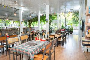 un restaurante con mesa, sillas, mesas y ventanas en Cat Ba Countryside Homestay, en Cat Ba