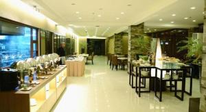 巴科洛德GT Hotel Bacolod的一间设有桌椅的餐厅和一个站在房间里的人