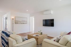 a living room with two chairs and a flat screen tv at Ocean Haze - Putting Green, Firepit, Beach location in Mollymook