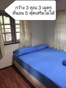 Bett mit blauer Bettwäsche in einem Zimmer mit Fenstern in der Unterkunft Baan I Mhok Suanphueng in Suan Phung