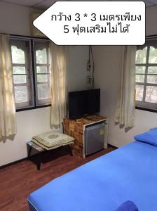 una camera con letto, TV e finestre di Baan I Mhok Suanphueng a Suan Phung