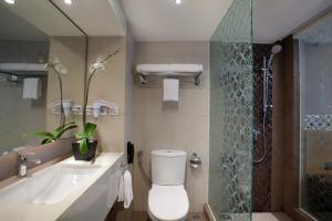 ein Badezimmer mit Toilette, Waschbecken und Dusche in der Unterkunft Ramada by Wyndham Bali Sunset Road Kuta in Kuta