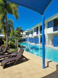 a resort swimming pool with chairs and palm trees at Reefside Escape Silkari Resort in Port Douglas