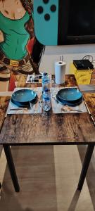 ein Holztisch mit blauen Tellern und Gläsern darauf in der Unterkunft Maison game in Villeneuve-sous-Dammartin