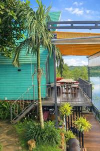 a house with a deck with a table and a palm tree at Hồ Mây Homestay in Bảo Lâm