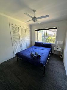 une chambre avec un lit bleu avec un ventilateur de plafond dans l'établissement Gold Coast Rooms, à Gold Coast