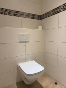 eine weiße Toilette in einem Badezimmer mit weißen Fliesen in der Unterkunft The Forest Green Residence with Garden & Tranquility in Oldenburg + 16 Fotos